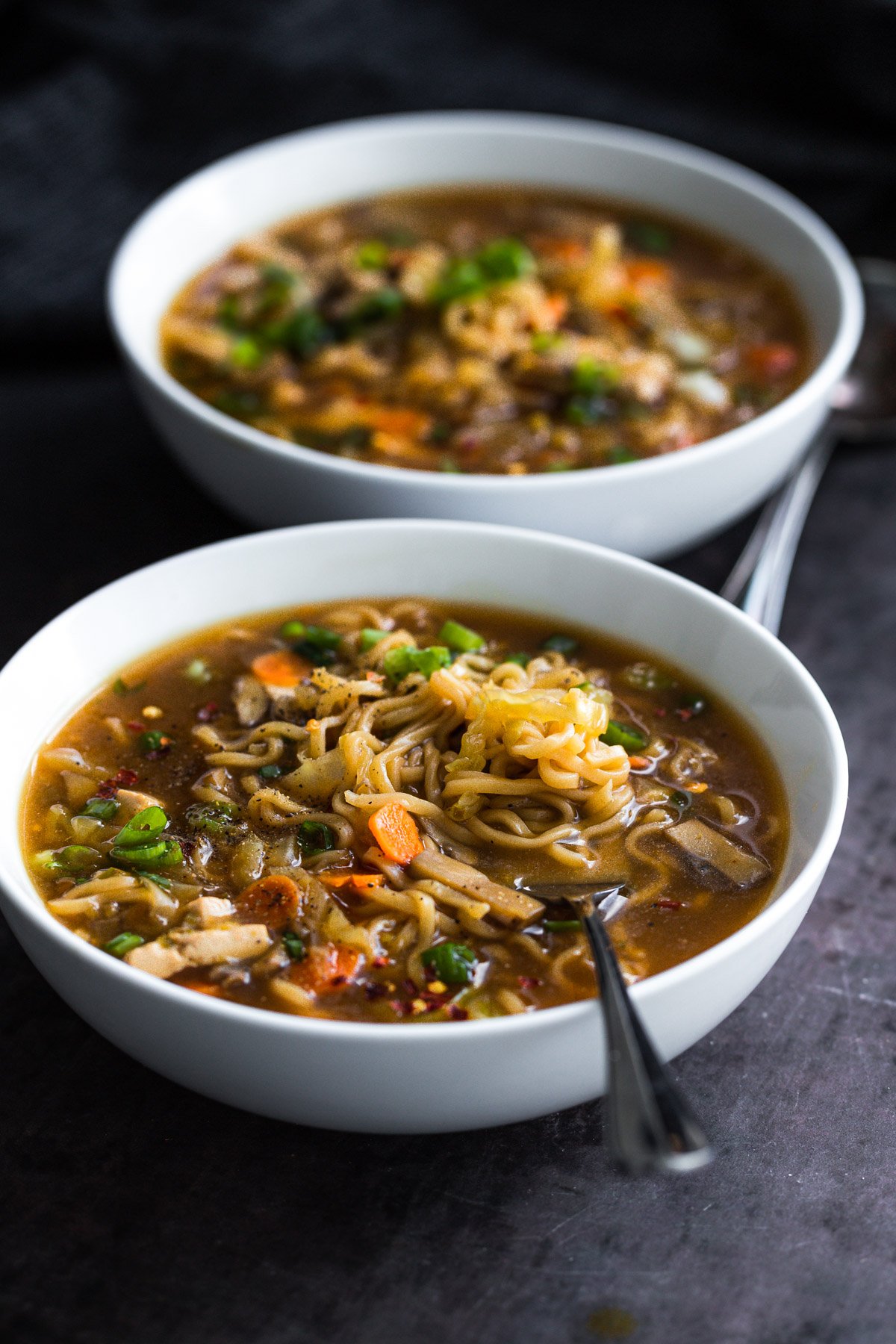 side view of a bowl of hot and sour ramen soup sprinkled with spring onions