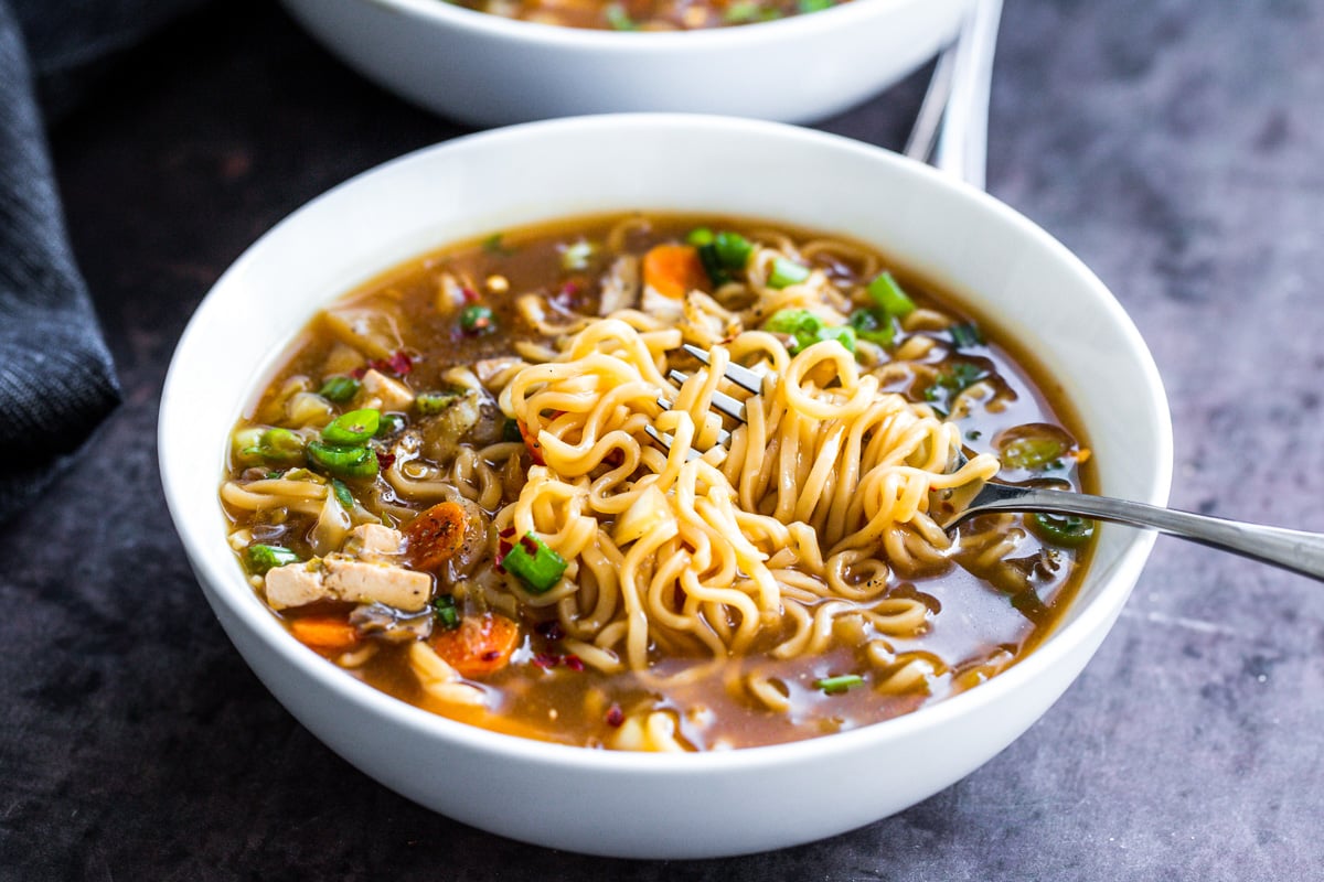 vegan hot and sour soup a fork twirling some ramen noodles in a bowl of hot and sour soup