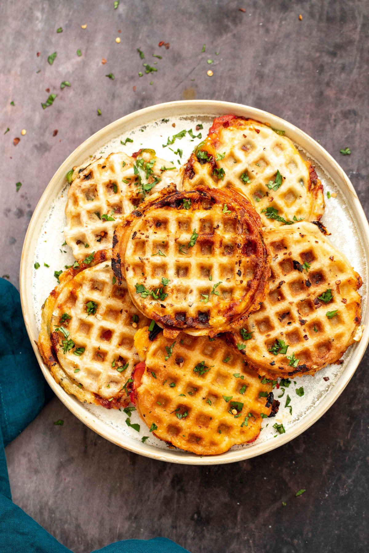 vegan pizza waffles a plate with homemade vegan pizza waffles sprinkled with herbs
