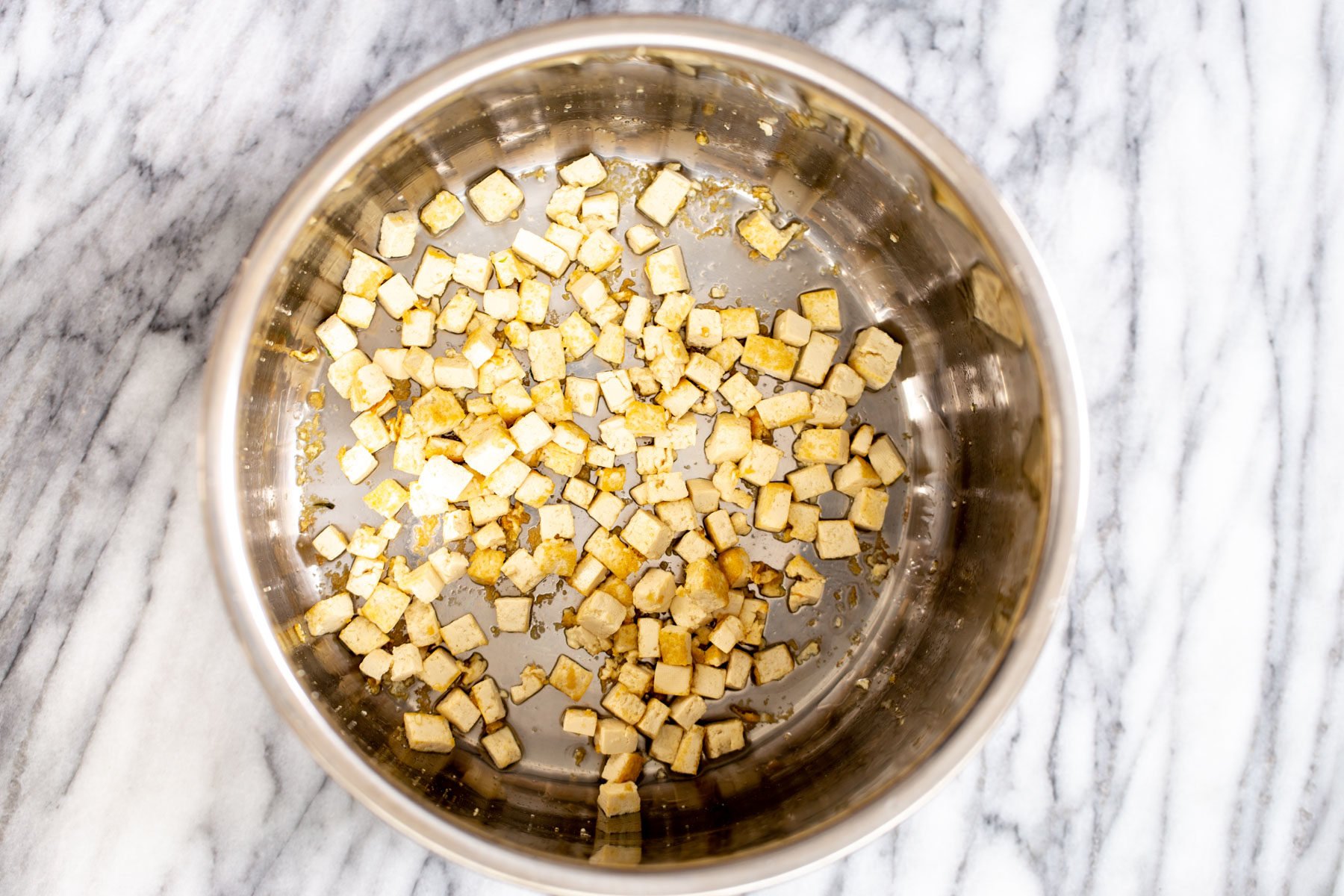 tofu cubes being fried in a pot