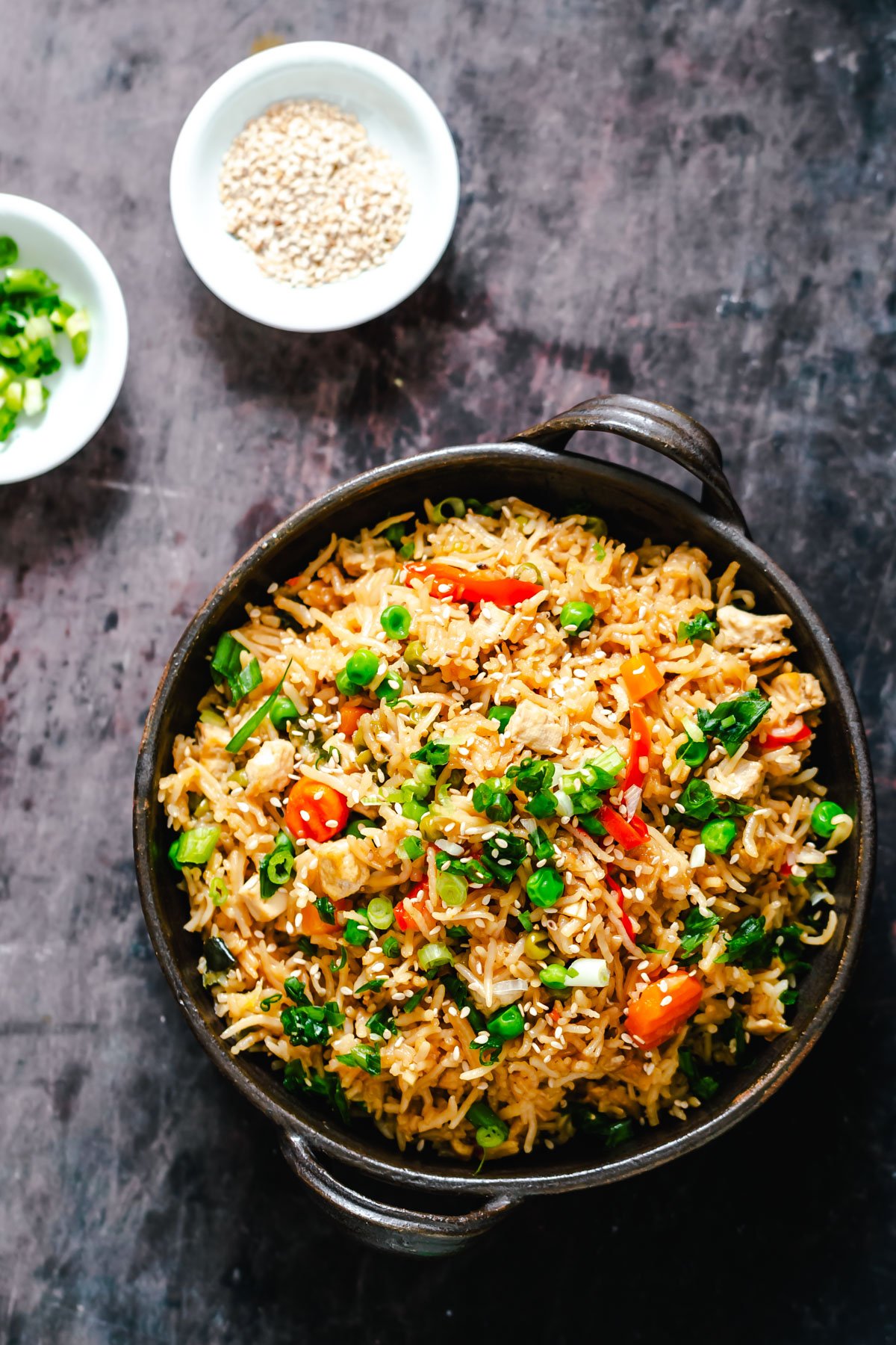 Instant Pot Teriyaki Fried Rice in a black dish with a small dish with green onions and sesame seeds on the side