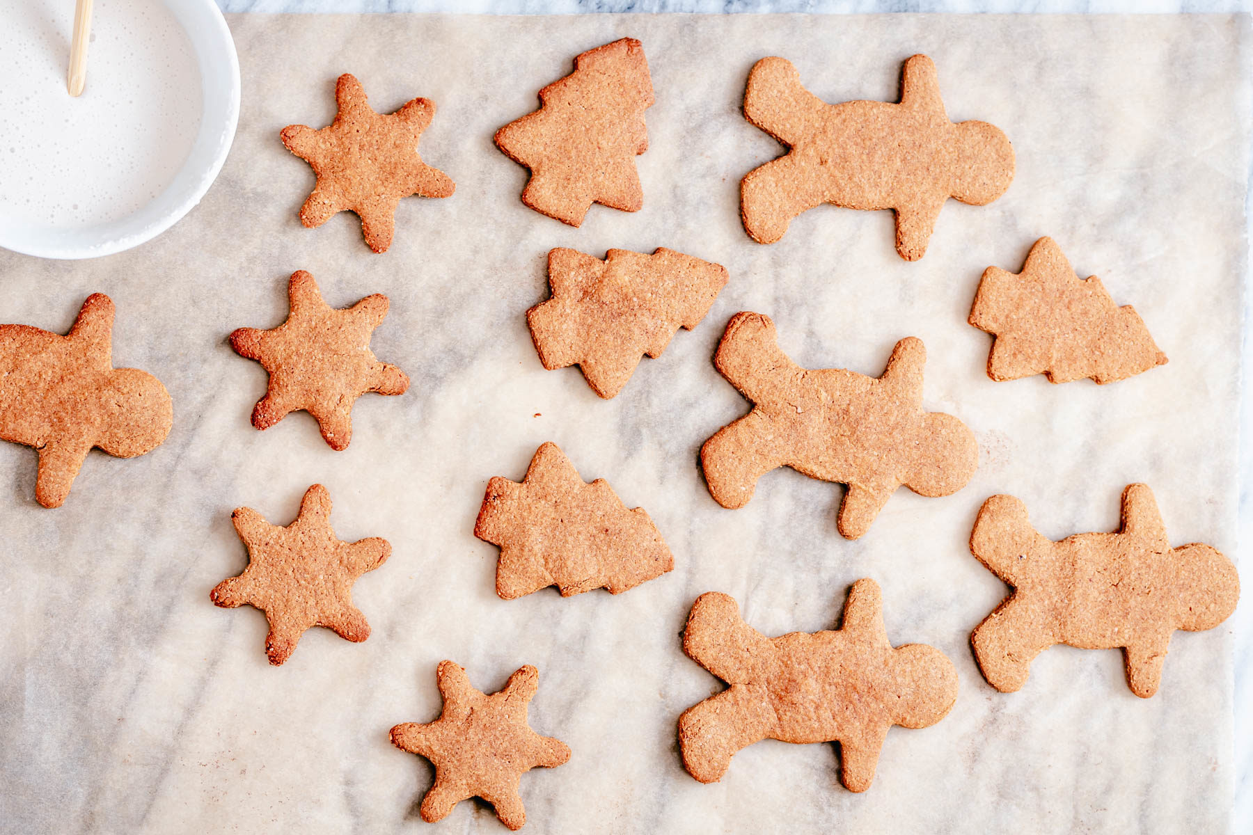vegan gingerbread cookies  vegan gingerbread cookies cooling on a countertop with small bowl of icing