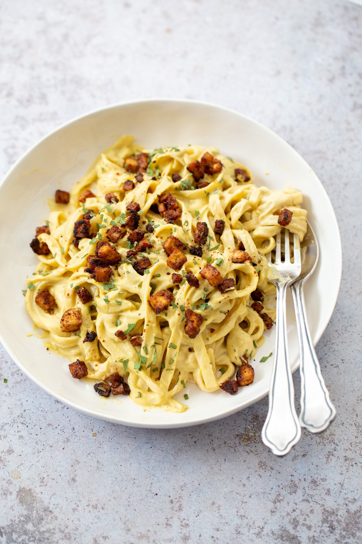 butternut squash carbonara  close up of a plate of vegan butternut squash pasta carbonara served with baked tofu