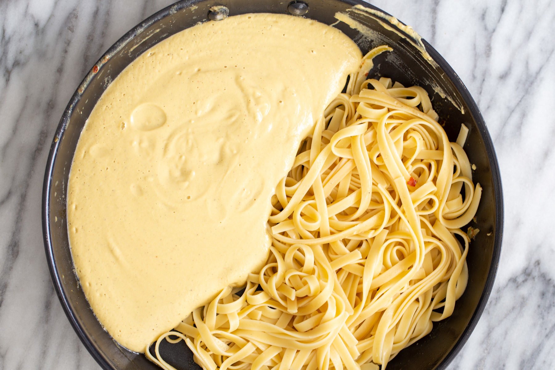butternut squash carbonara  overhead shot of a skillet with linguine with creamy butternut squash carbonara sauce