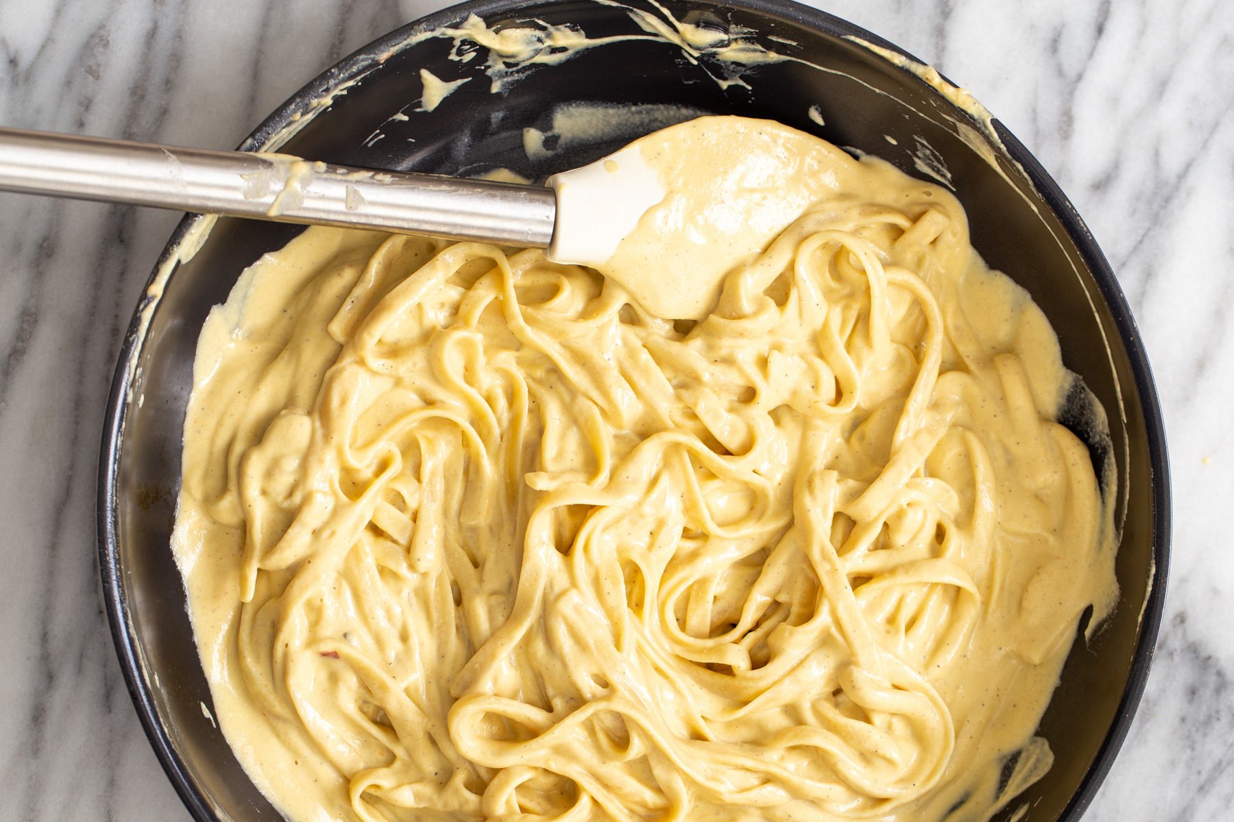 butternut squash carbonara  fettuccine being tossed in vegan butternut squash cashew cheese carbonara sauce