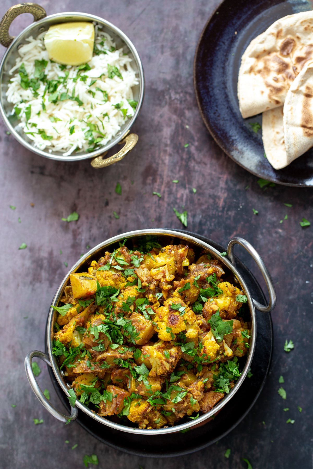 vegan aloo gobi  a small pot of rice and an indian dish with vegan aloo gobi on a wooden surface