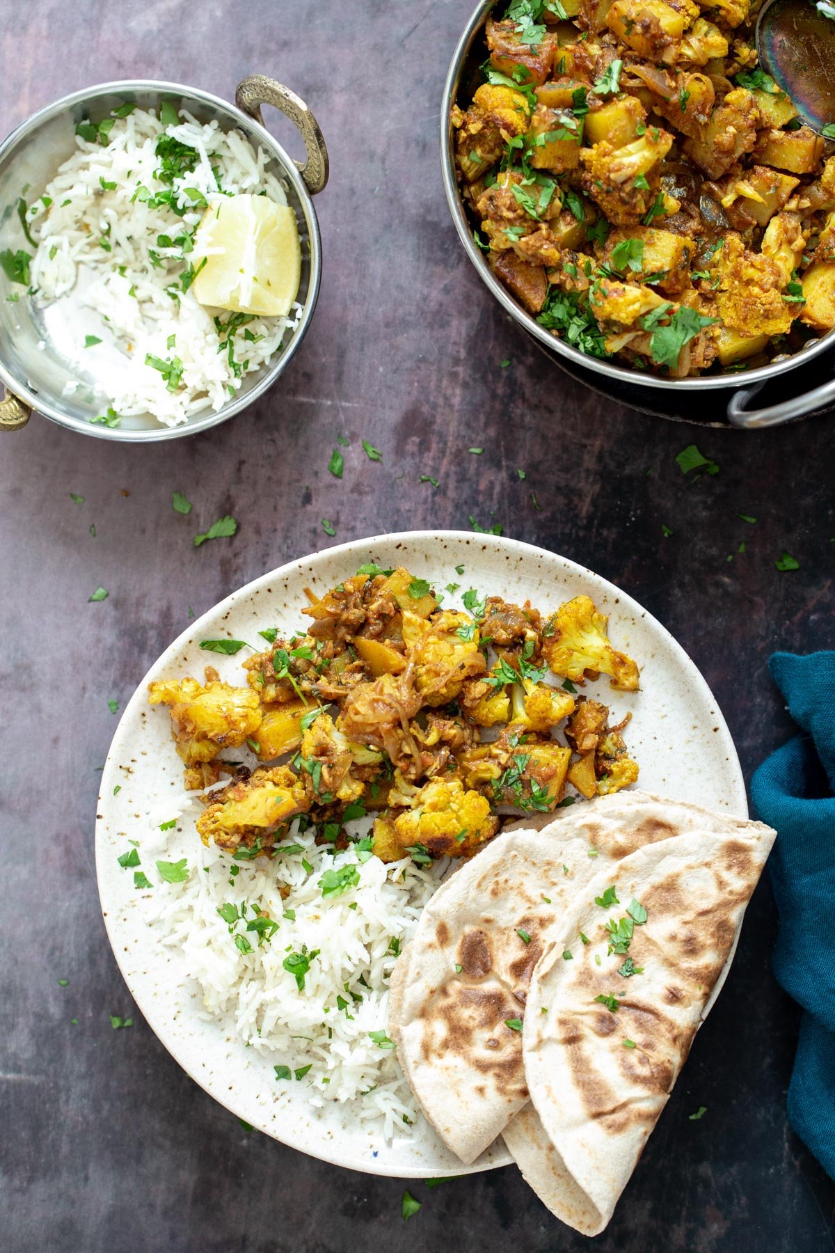 vegan aloo gobi  a plate with a serving of aloo gobi, rice and 2 folded naan breads