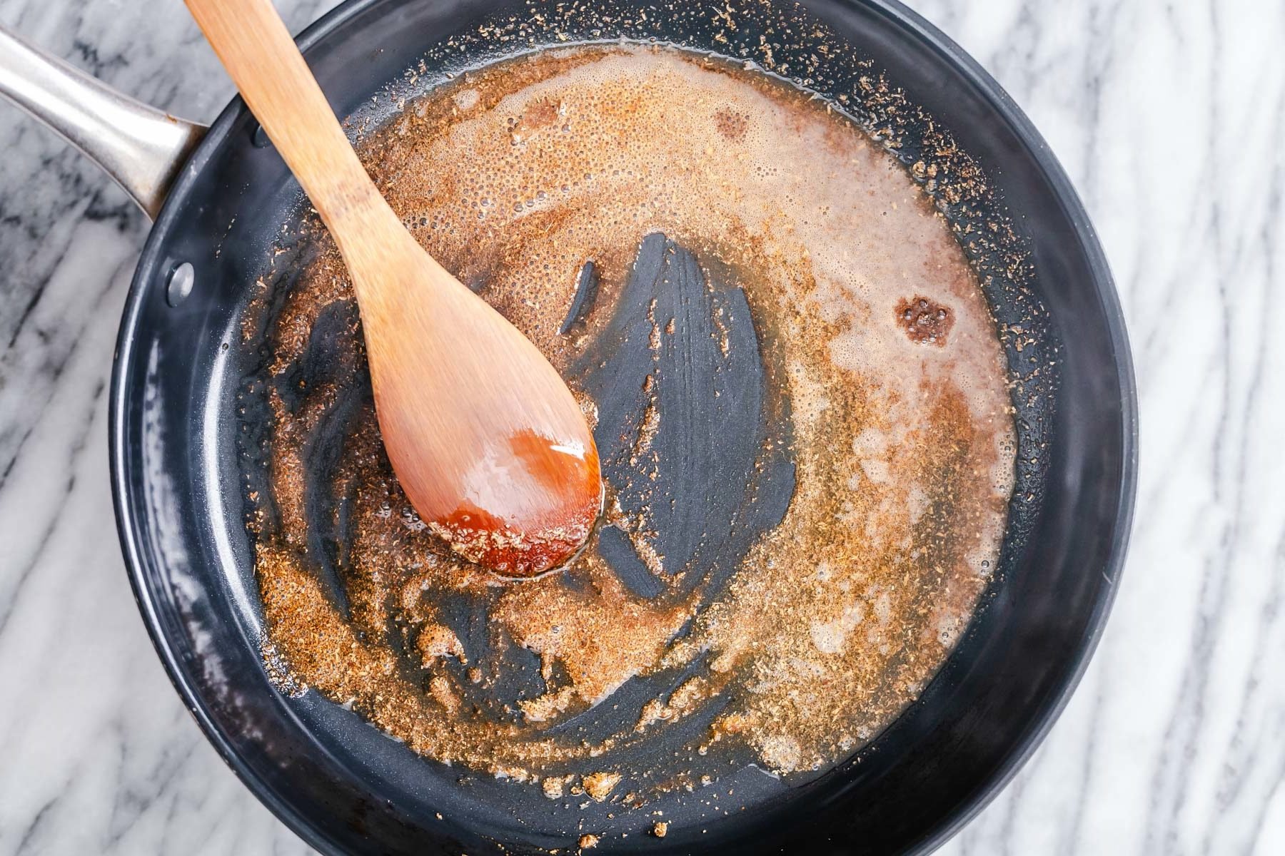 vegan aloo gobi  Indian spices being tempered in a black frying pan