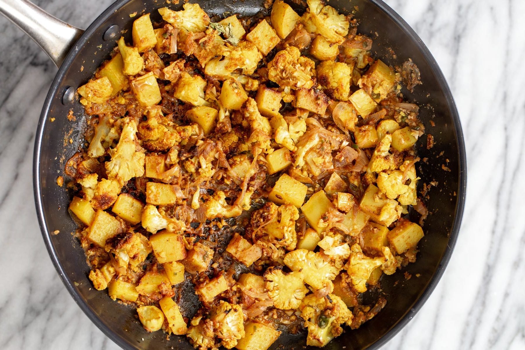 vegan aloo gobi cauliflower and potato cubes being sauteed in onion garlic and tomato
