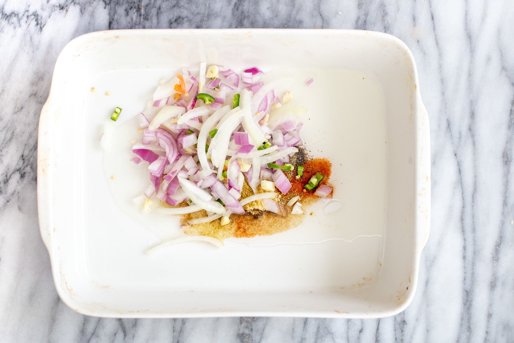 vegan vegetable casserole oil, spices onion, chili and garlic in a white casserole dish