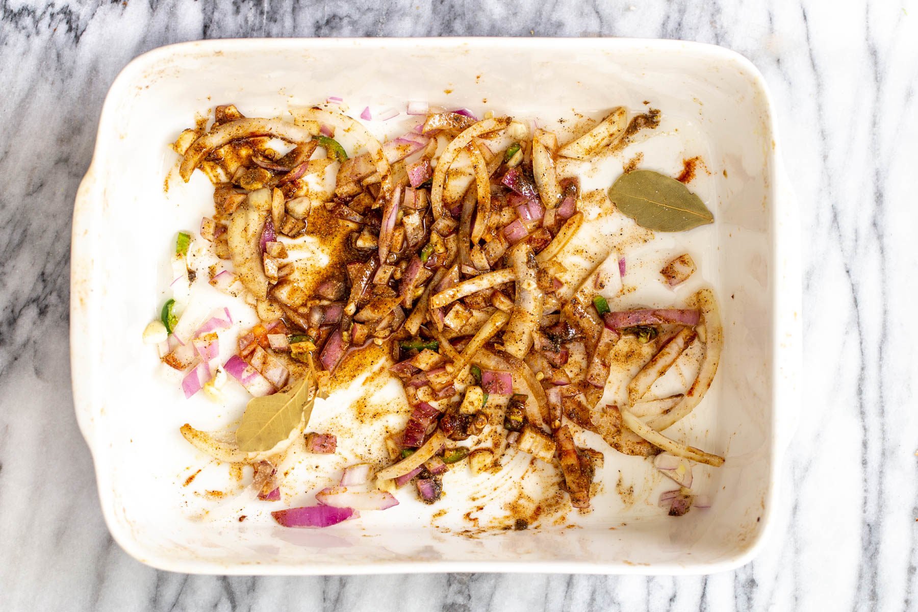 vegan vegetable casserole onion, garlic and spices baking in a white casserole dish
