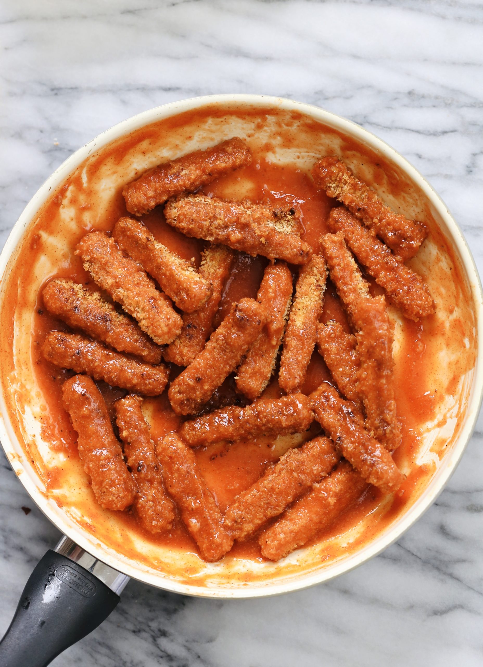 overhead shot of a skillet with vegan baked firecracker tofu wings tossed firecracker sauce