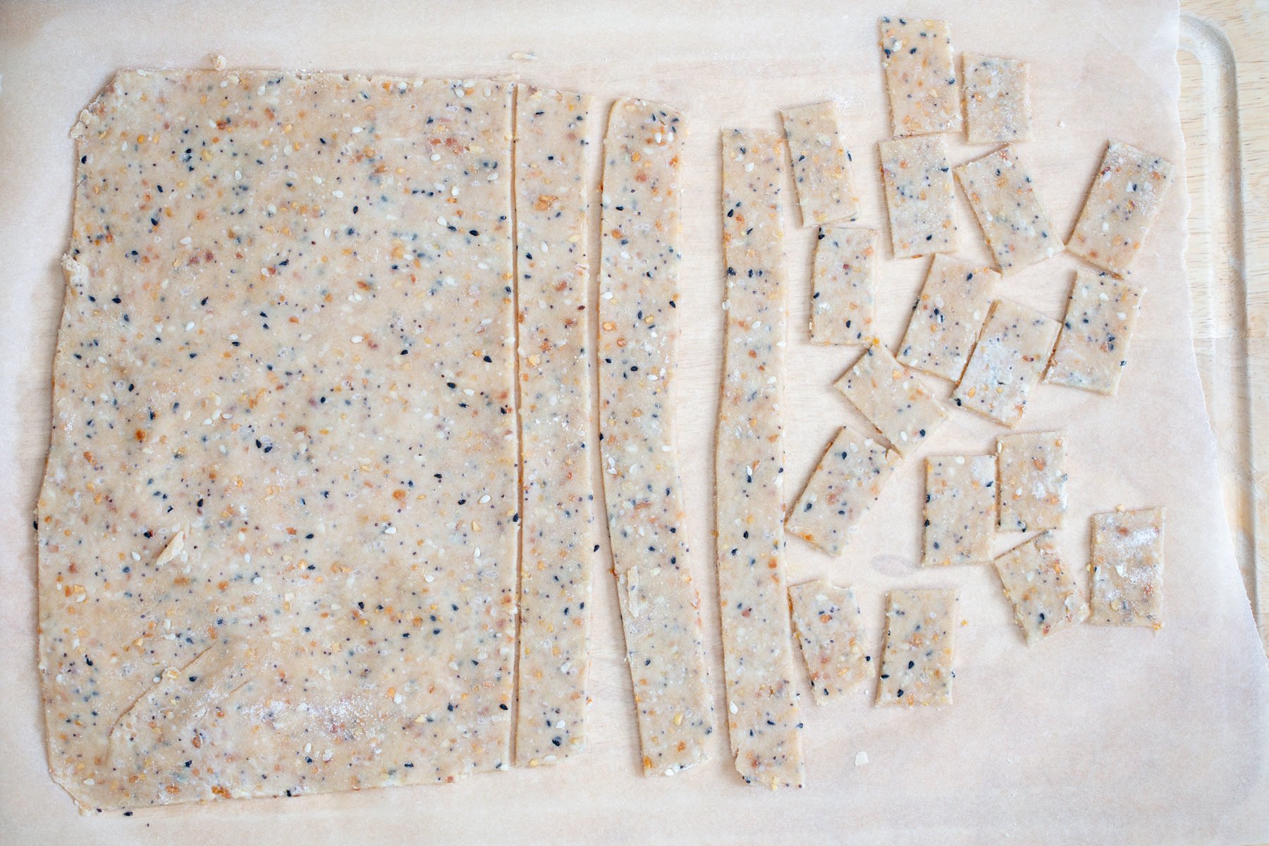 vegan bagel cracker dough being rolled out an cut into small squares
