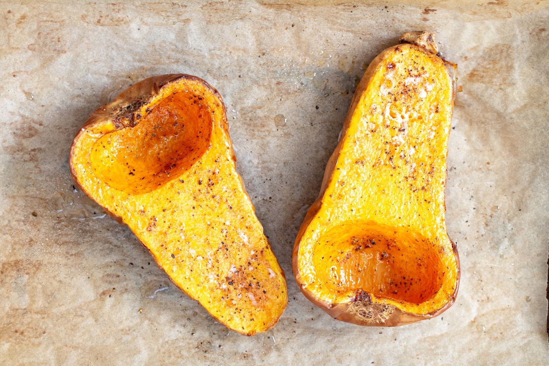 two baked halves of vegan butternut squash ready for stuffing