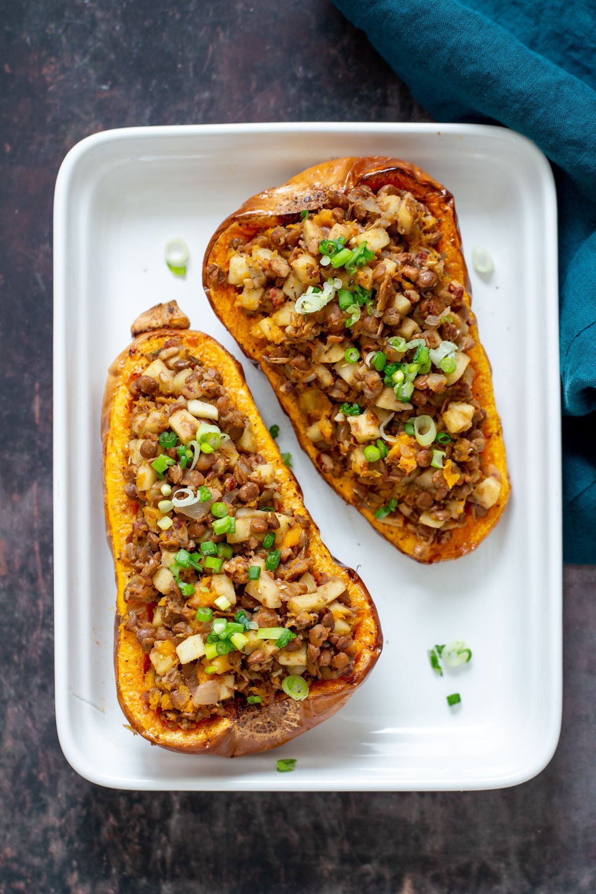 vegan stuffed butternut squash lentil and apple stuffed butternut squash halves in a white casserole dish