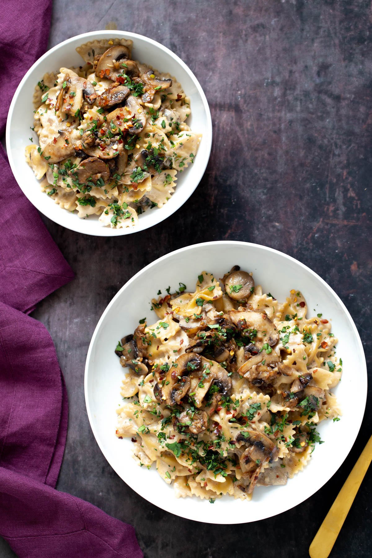 vegan mushroom stroganoff two plates with farfalle pasta topped with vegan mushroom stroganoff