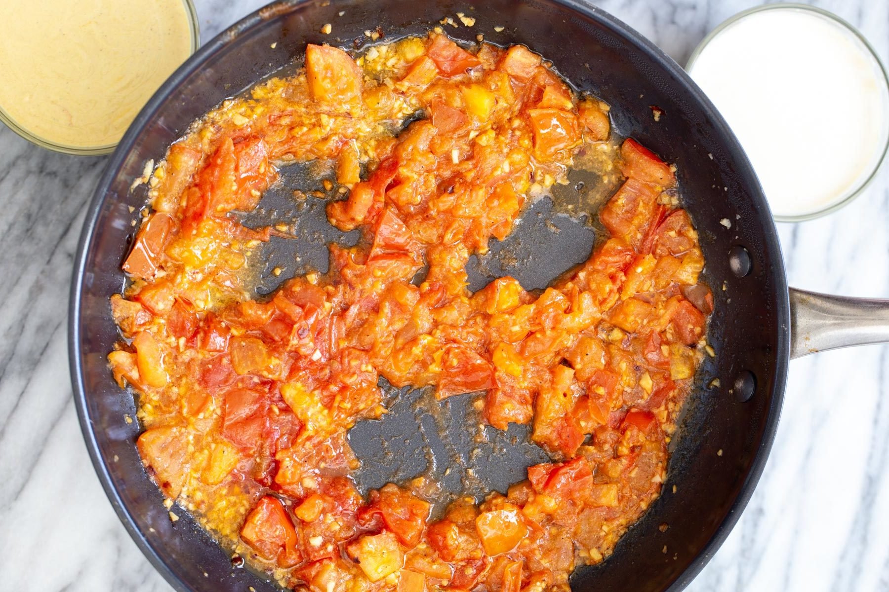 vegan eggs in purgatory tomato sauce in a sauteeing pan being pushed aside to make room for tofu eggs