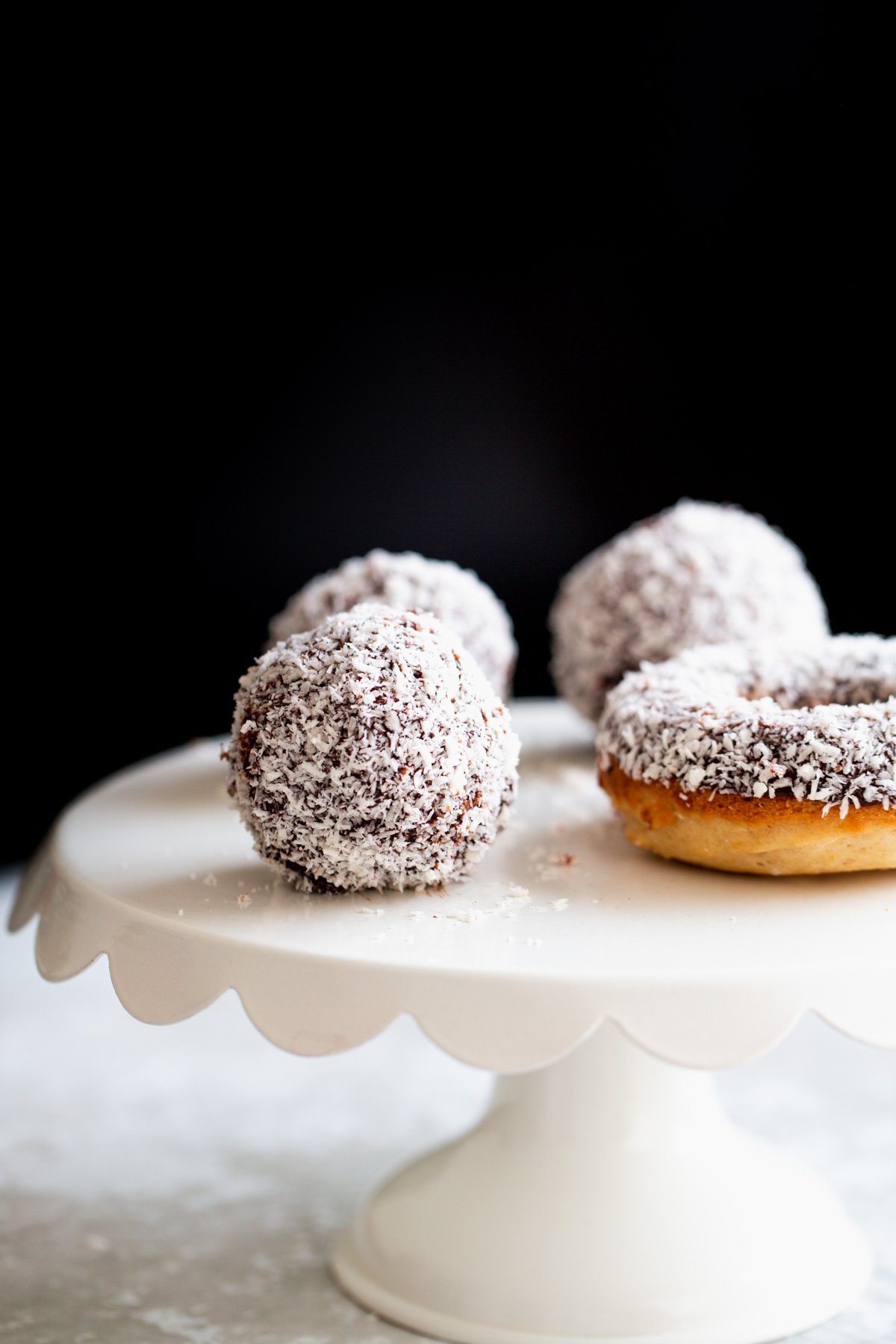 lamington donuts vegan lamington donut holes and baked donuts on a white cake stand
