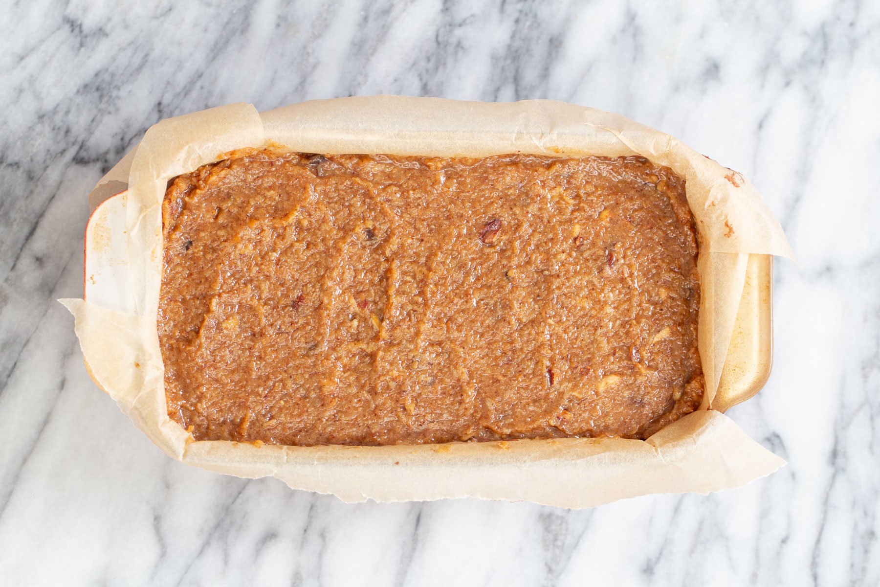 coconut caramel layer being spread on top of cake layer to make german chocolate loaf