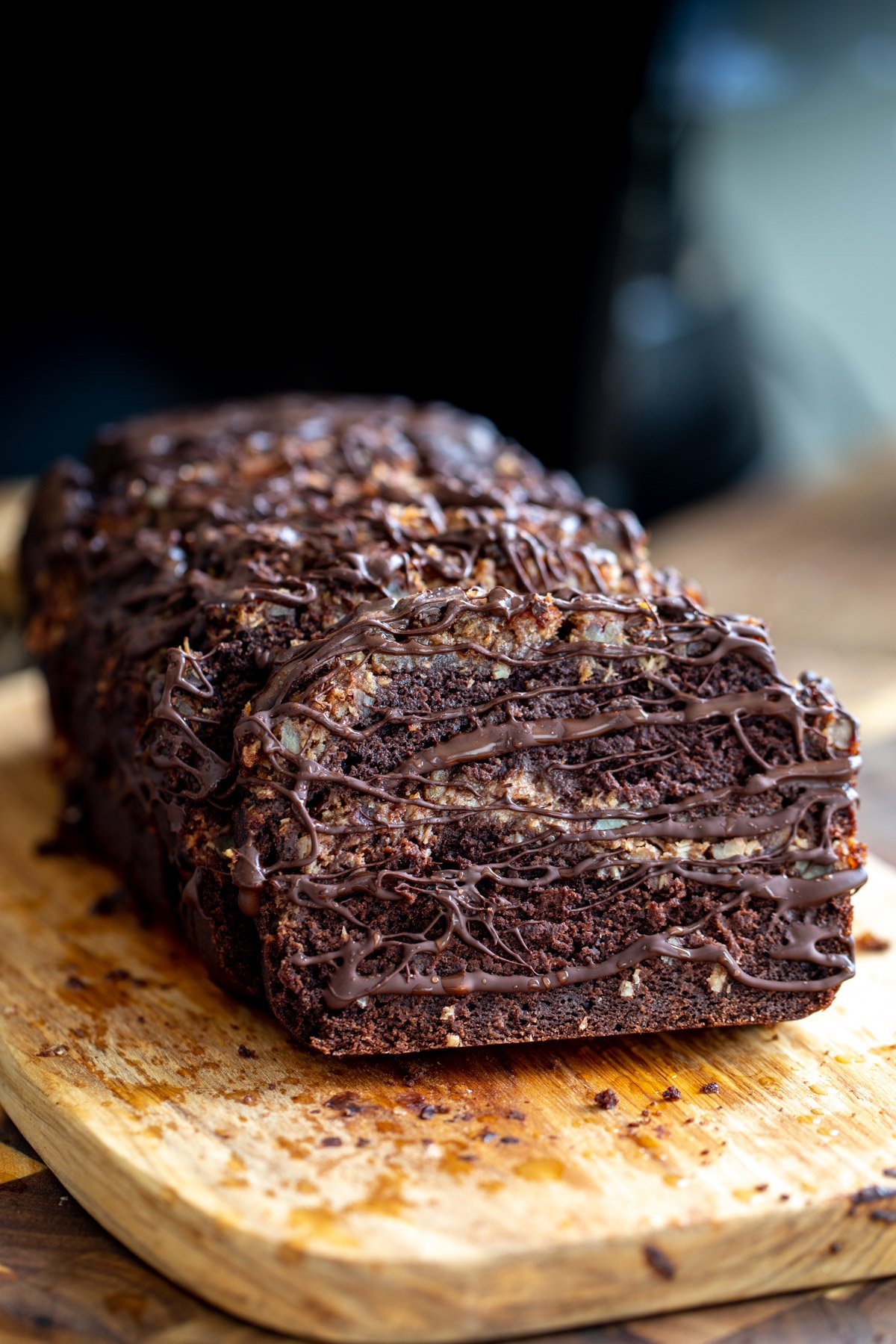 vegan German Chocolate loaf cake being drizzled with melted dark chocolate