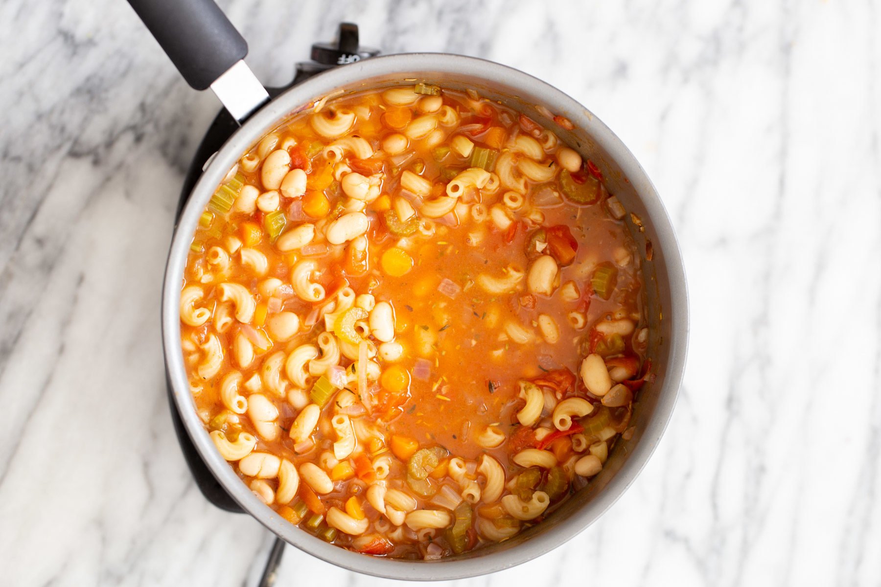 pasta e fagioli pasta and white beans simmering in tomato broth in a saucepan