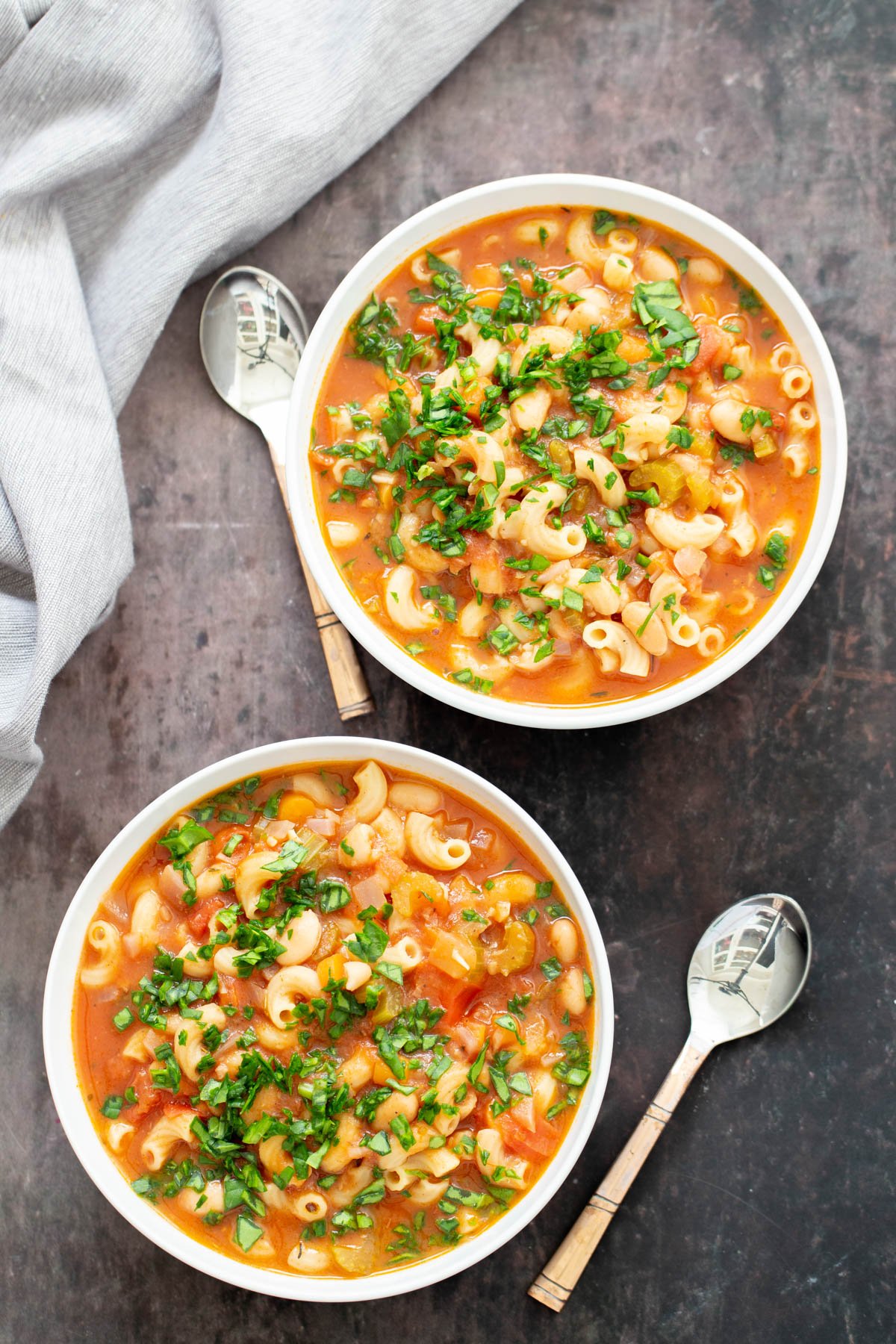 vegan paste e fagioli  overhead shot of two bowls of vegan pasta e fagioli garnished with chopped basil