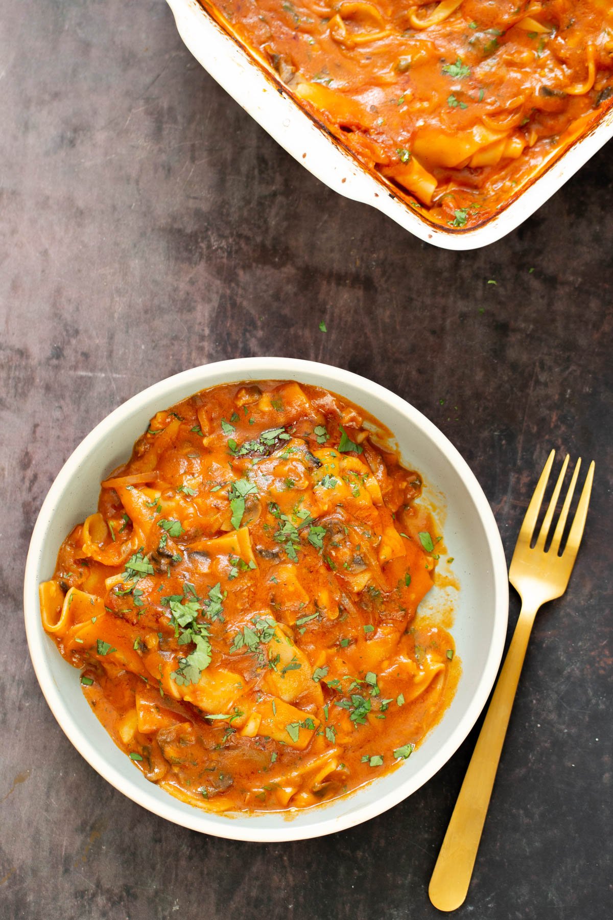 a bowl with butter chicken lasagna next to a casserole dish with lasagna