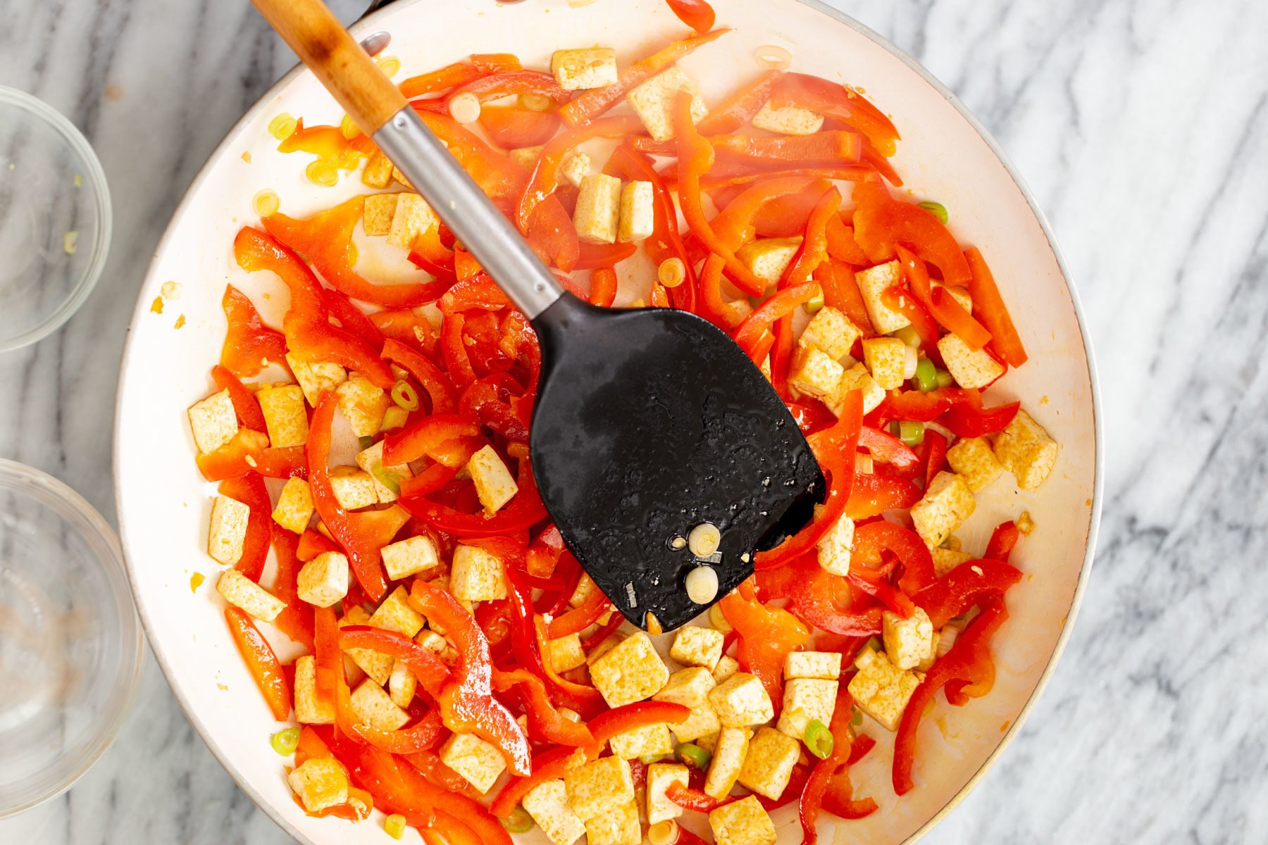tofu and bell pepper being sauteed in a frying pan