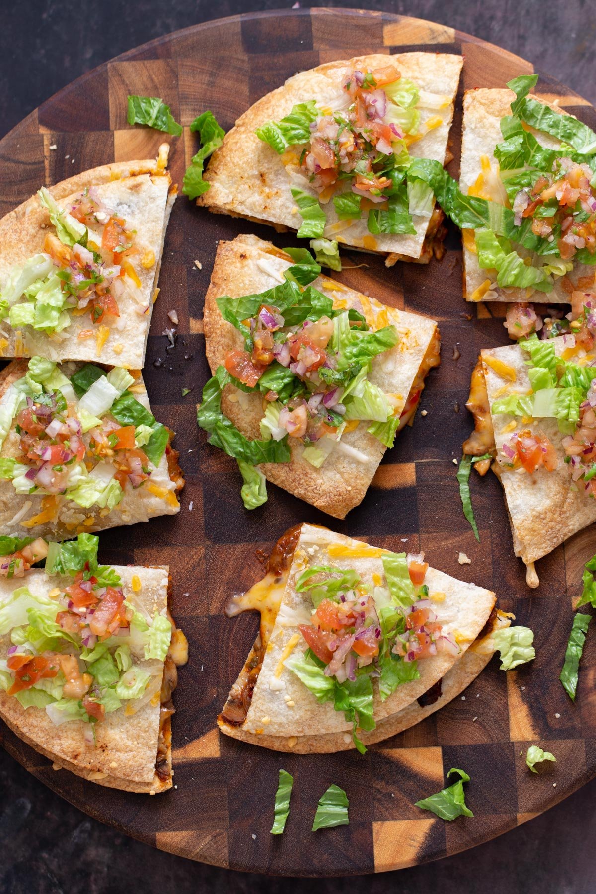 vegan mushroom quesadilla cut into wedges and topped with salsa and romaine served on a wooden board