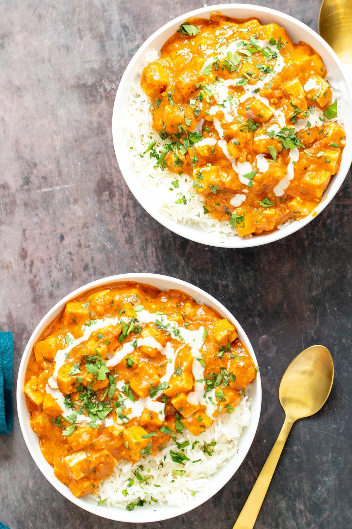two bowls with vegan tofu curry casserole served with rice with a spoon on the side