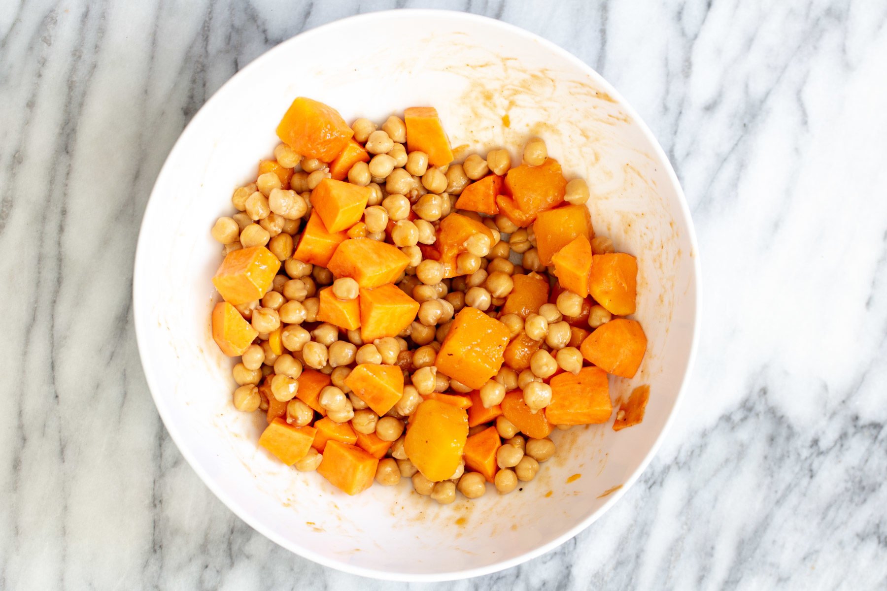sweet potato and chickpeas being mixed in a bowl for salad recipe