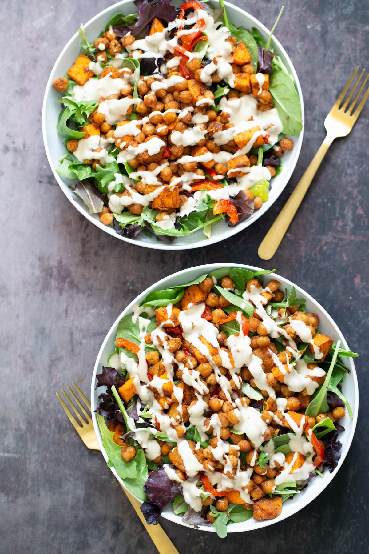 sweet potato salad  sweet potato chickpea salad served in two white bowls drizzled with tahini dressing