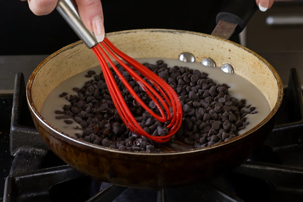 adding chocolate chips to the melted coconut cream