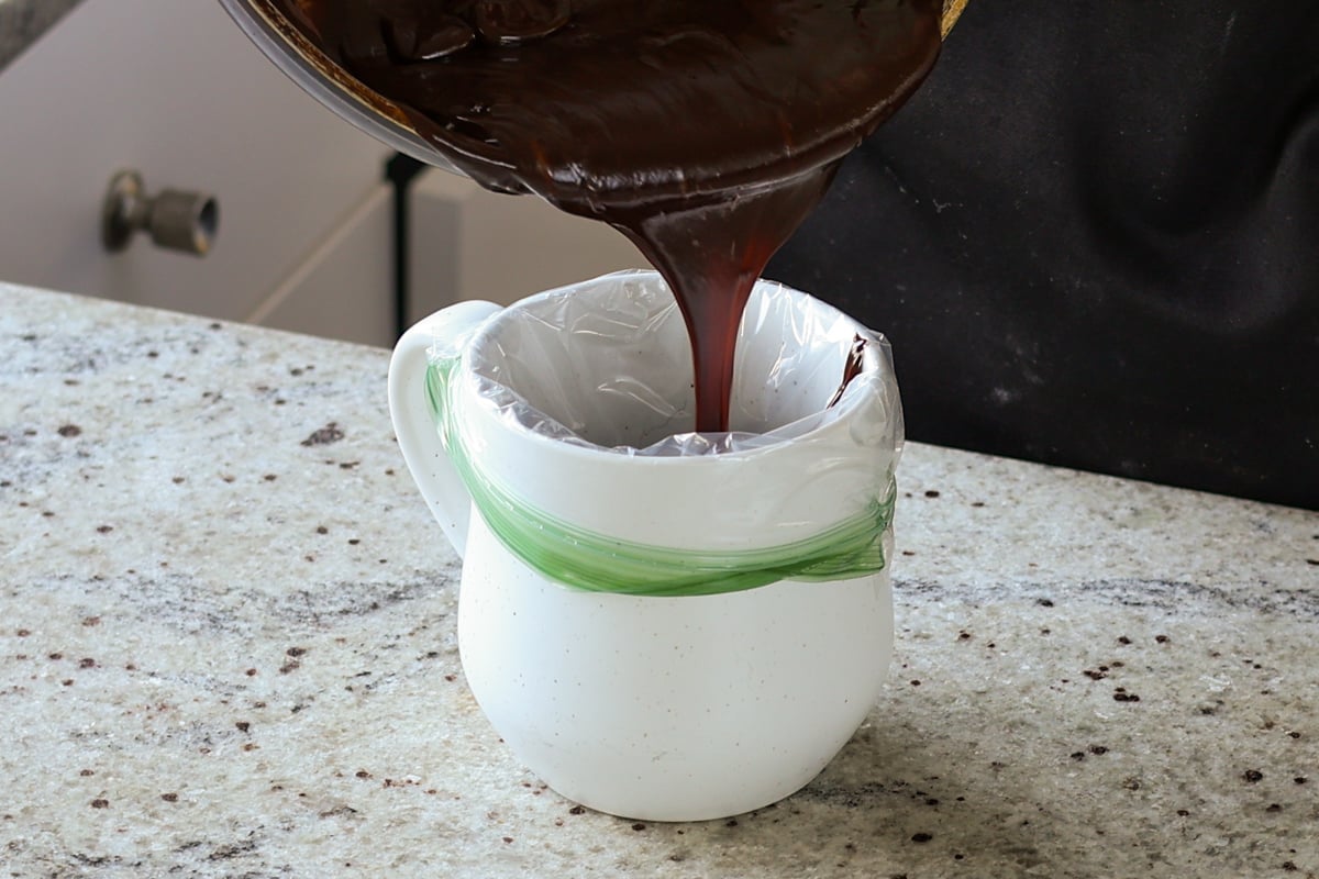 transferring chocolate ganache frosting to a plastic bag for piping