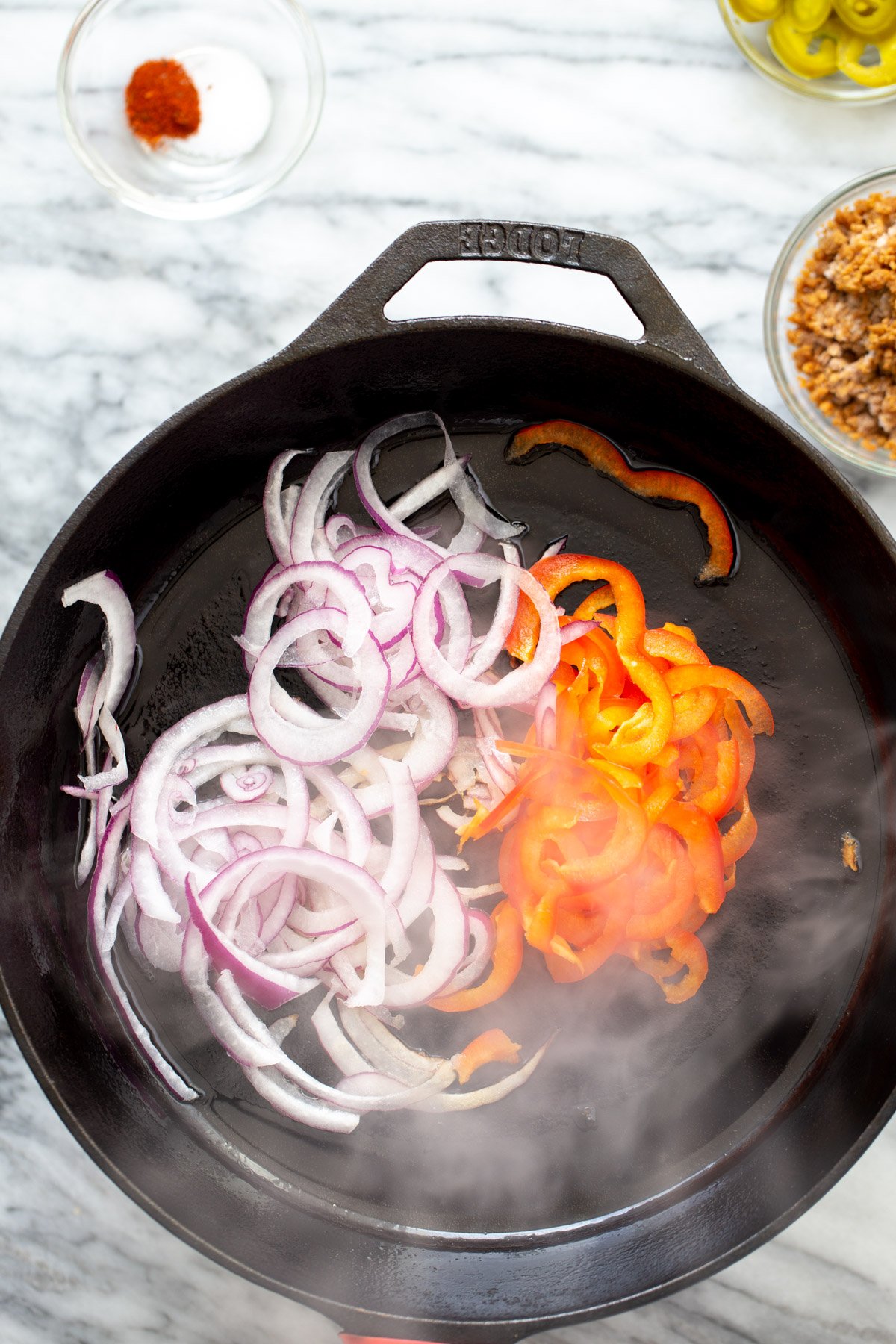 onions and bell pepper sauteeing in a skillet
