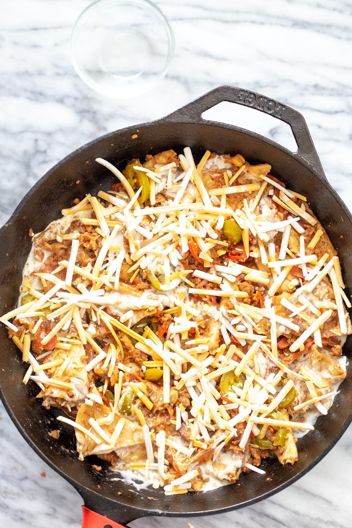 vegan jalapeno popper skillet covered with shredded cheese ready to be cooked