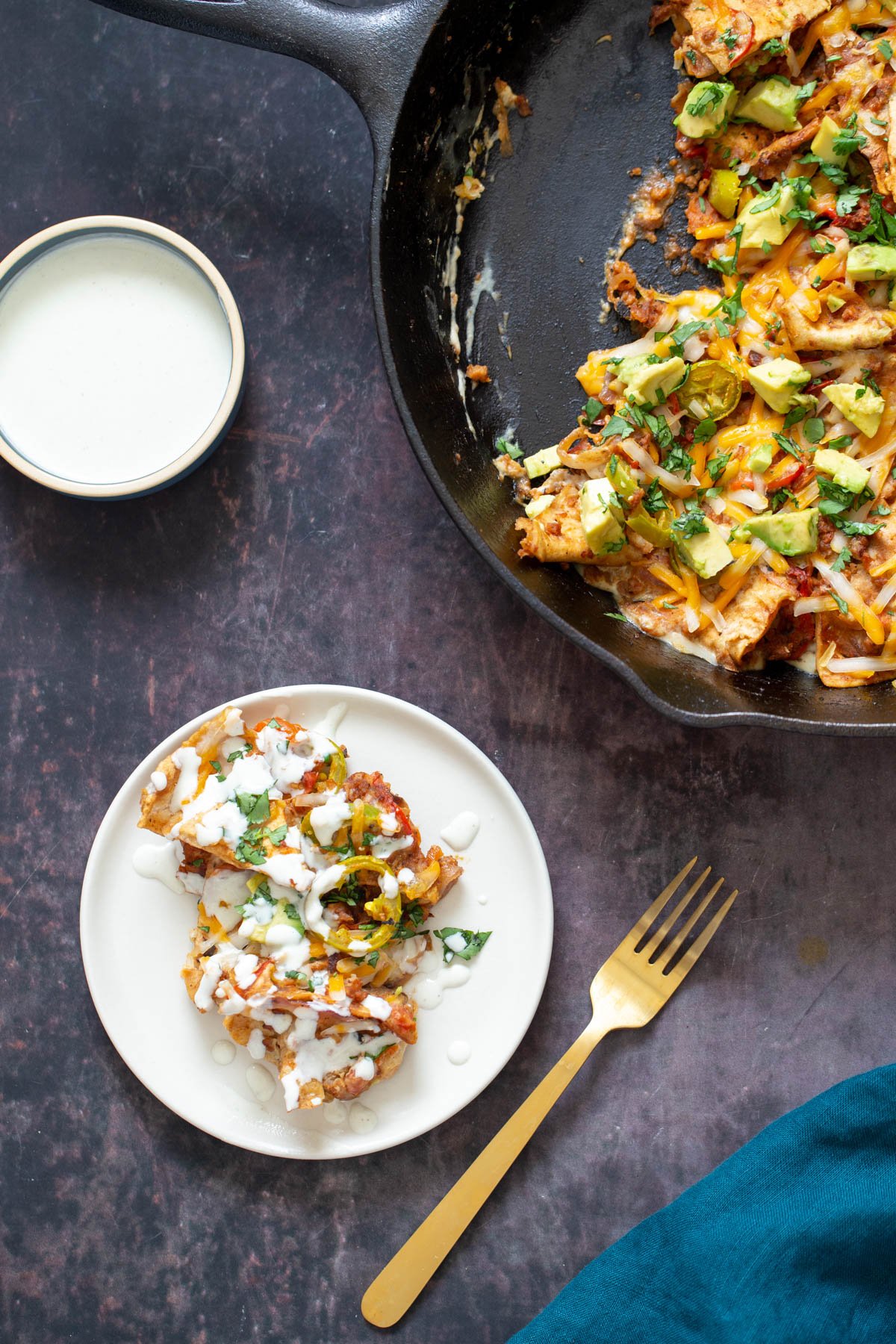 jalapeno popper skillet a serving of vegan jalapeno popper skillet served on a small white plate next to a skillet and a dish with cashew cream
