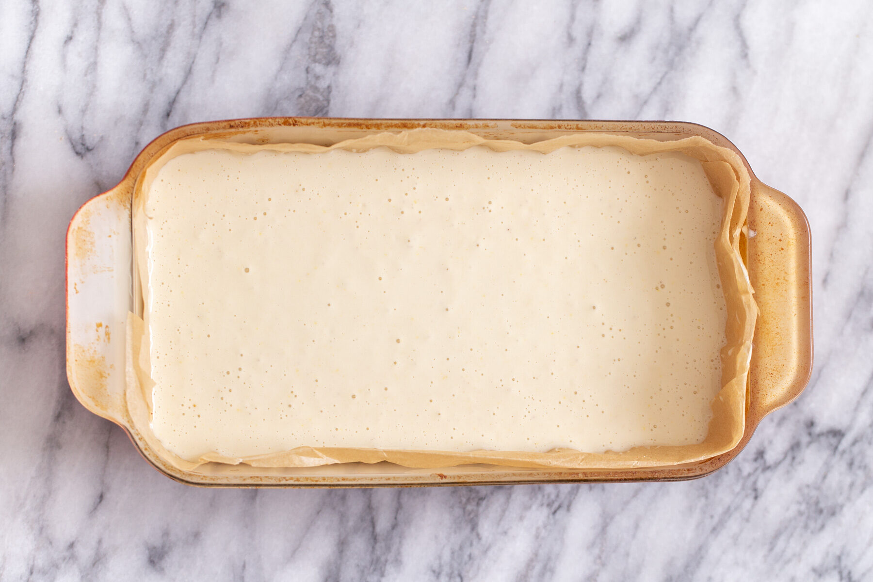 vegan lemon bars  vegan lemon cream filling being poured in a pyrex loaf pan to make lemon bars