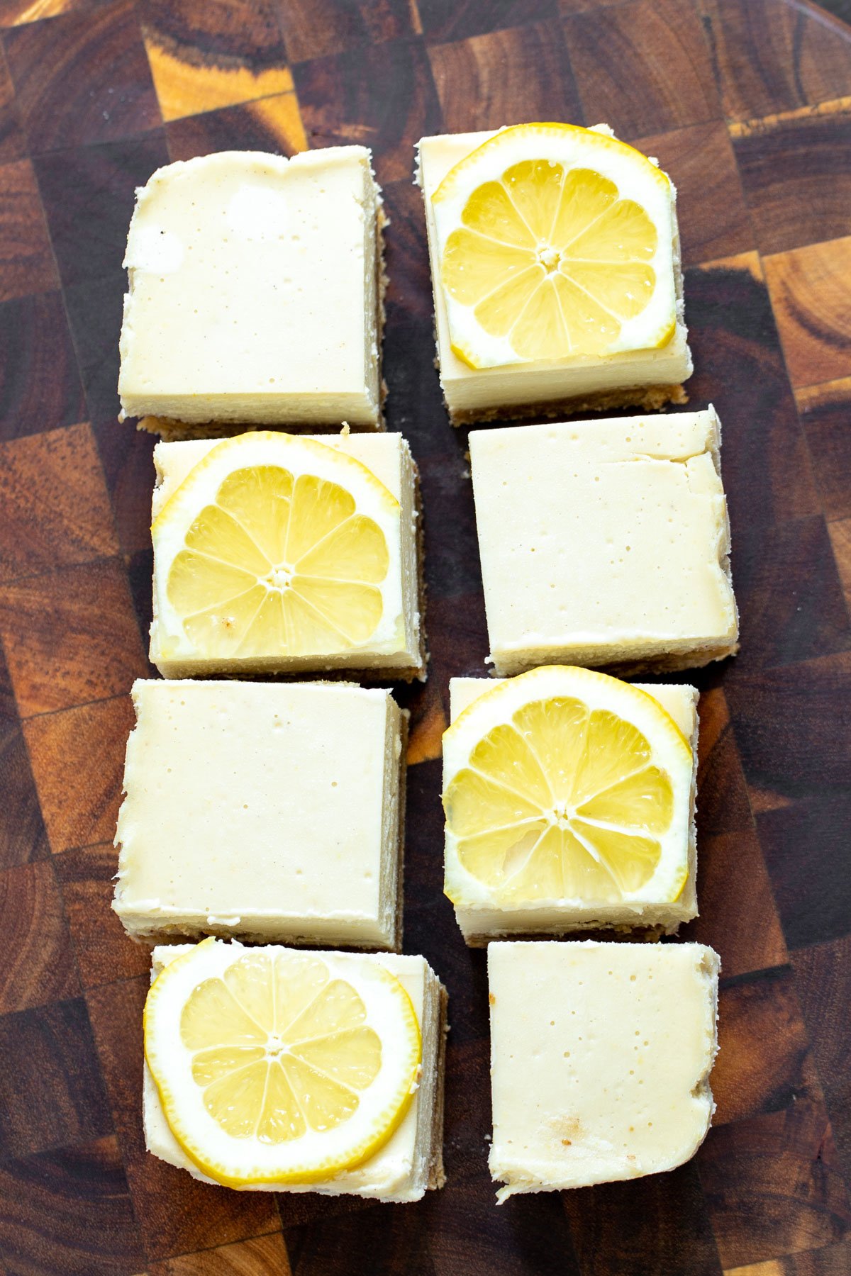 vegan lemon bars  vegan lemon bars on a wooden chopping board topped with lemon slices