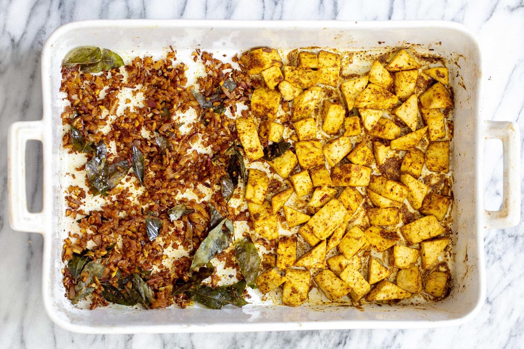 casserole dish with spiced baked tofu on one side and onions on the other side