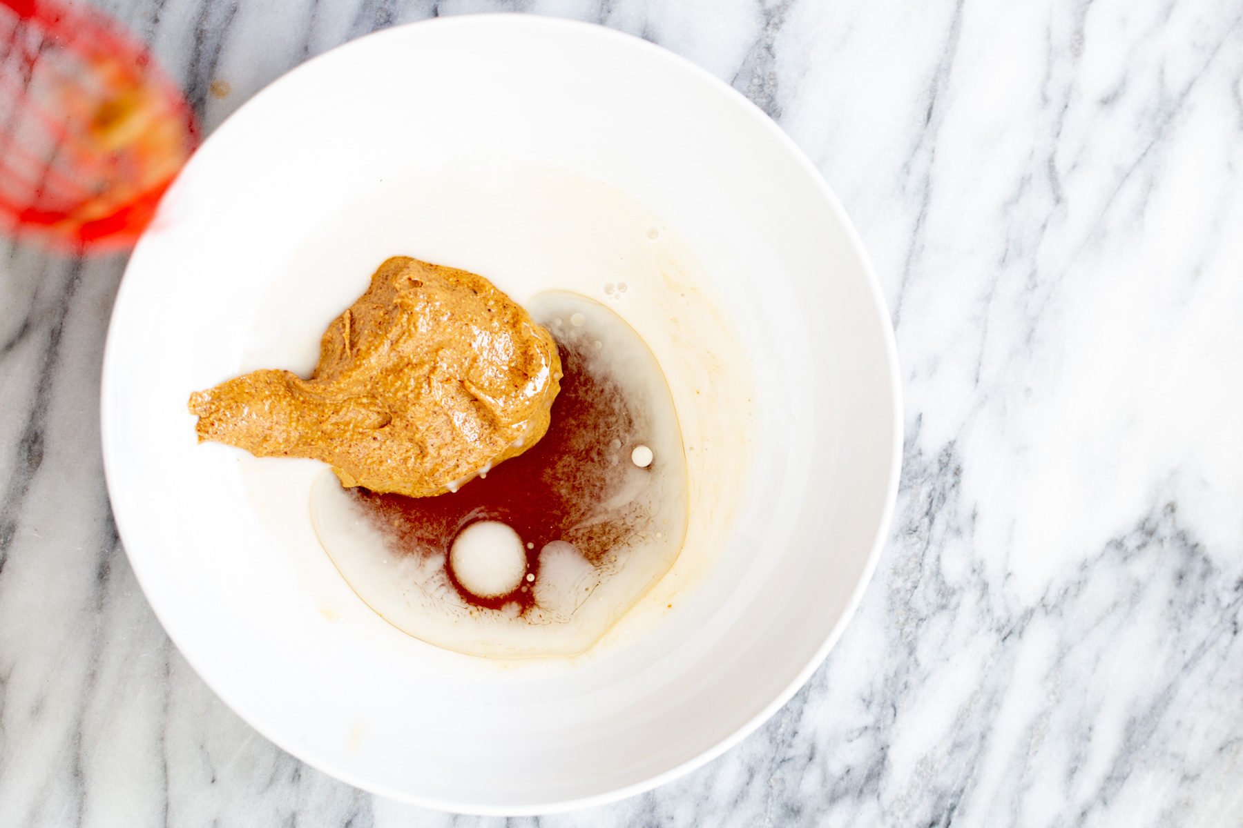 vegan date caramel oatmeal cookie bar ingredients being mixed in a small white bowl 