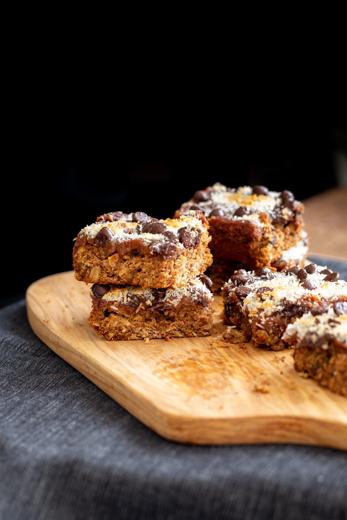 Front shot of vegan date caramel bars topped with chocolate chips and shredded coconut