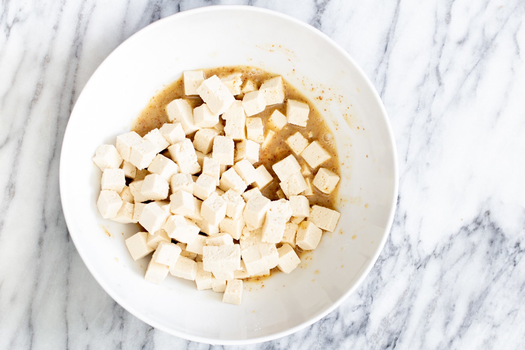 tofu cubes being mixed with marinade