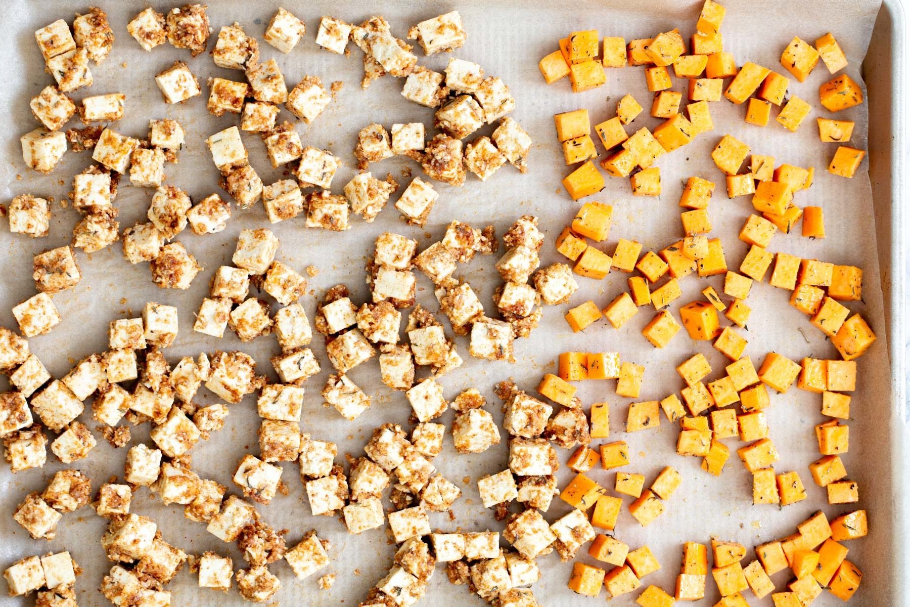 tofu and sweet potato cubes on a baking sheet ready to be baked