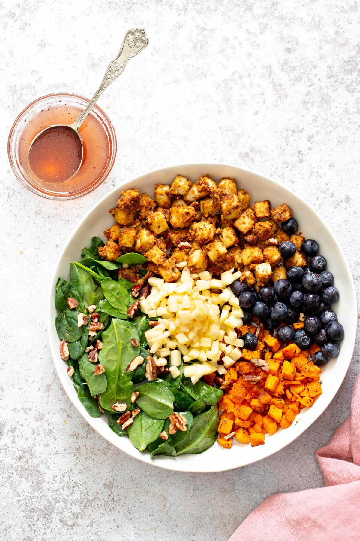 sweet potato tofu bowls all ingredients for sweet potato tofu bowls assembled in a shallow white bowl with a side dish with dressing