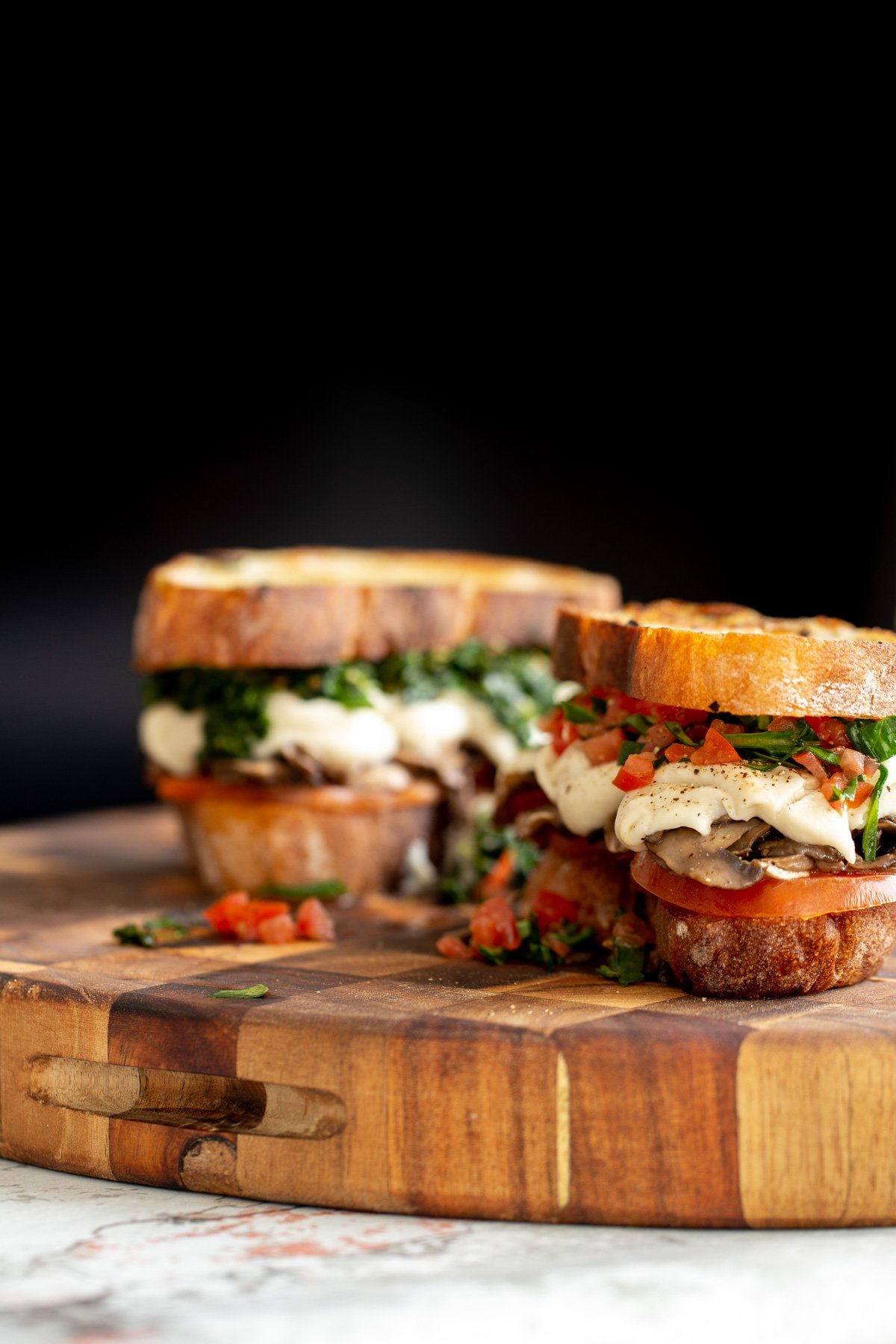 two vegan cheese melts on a wooden cutting board