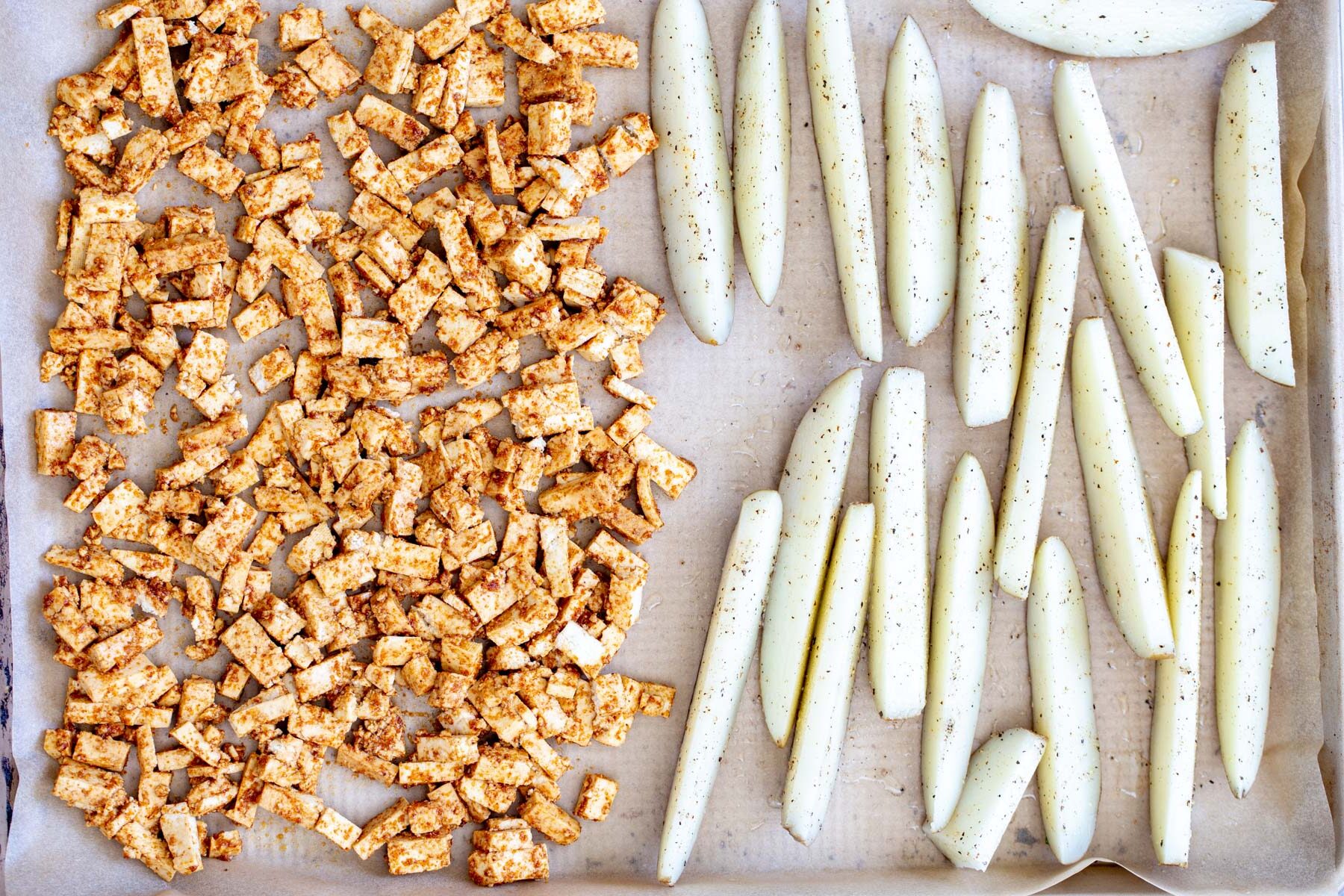 loaded potato wedges  baking sheet with marinated tofu cubes and seasoned potato wedges