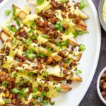 baked potato wedges topped with vegan cashew cheese sauce and tofu bacon bits