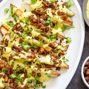 baked potato wedges topped with vegan cashew cheese sauce and tofu bacon bits
