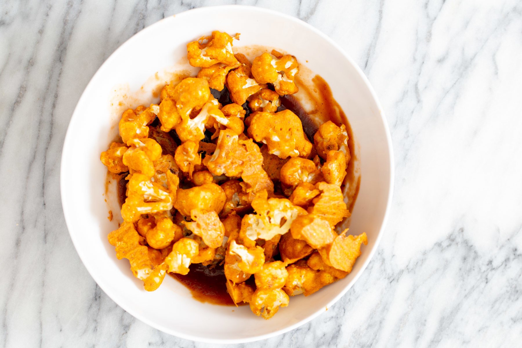 cauliflower wings  beer battered baked cauliflower wings being tossed in hot sauce and bbq sauce